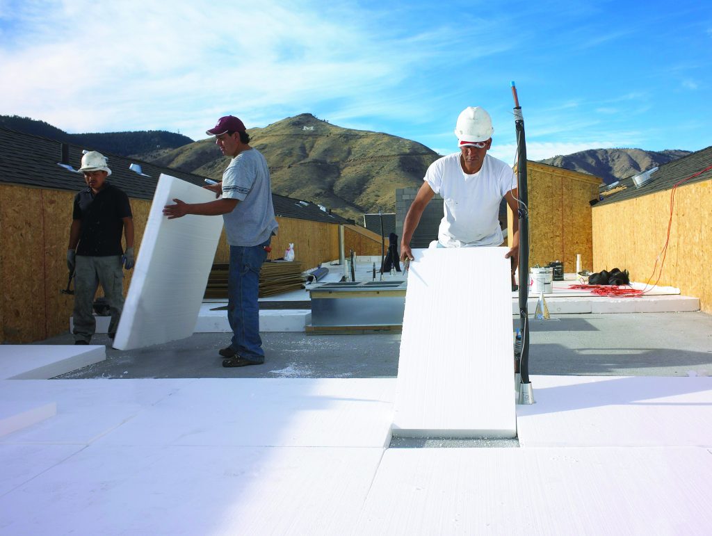 Installing rigid EPS insulation panels on a flat commercial roof during construction
