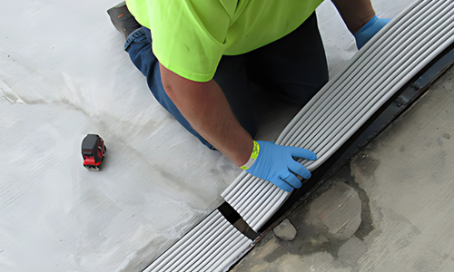 Worker installing pre-compressed joint sealant on concrete slab